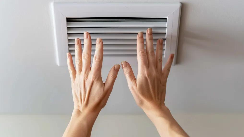 Woman placing hands over air vent