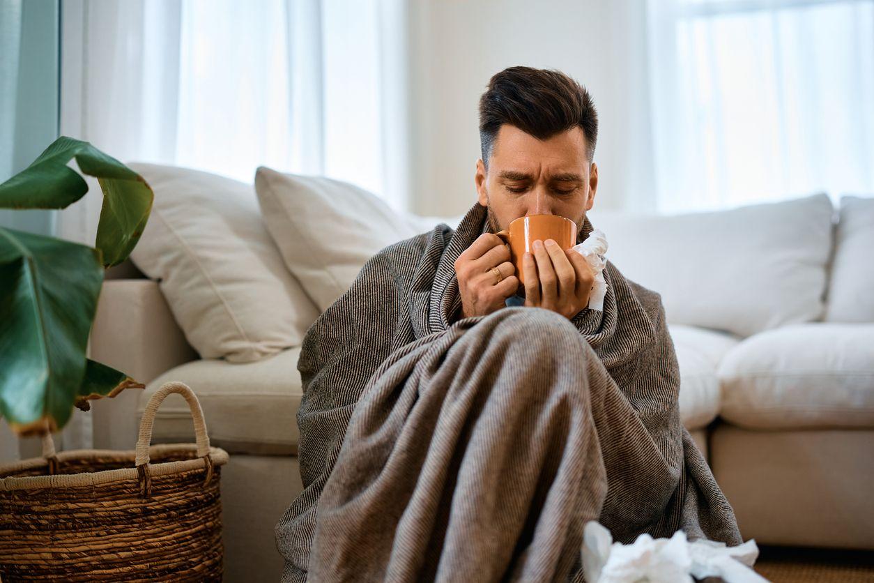 Man with cold drinking tea at home