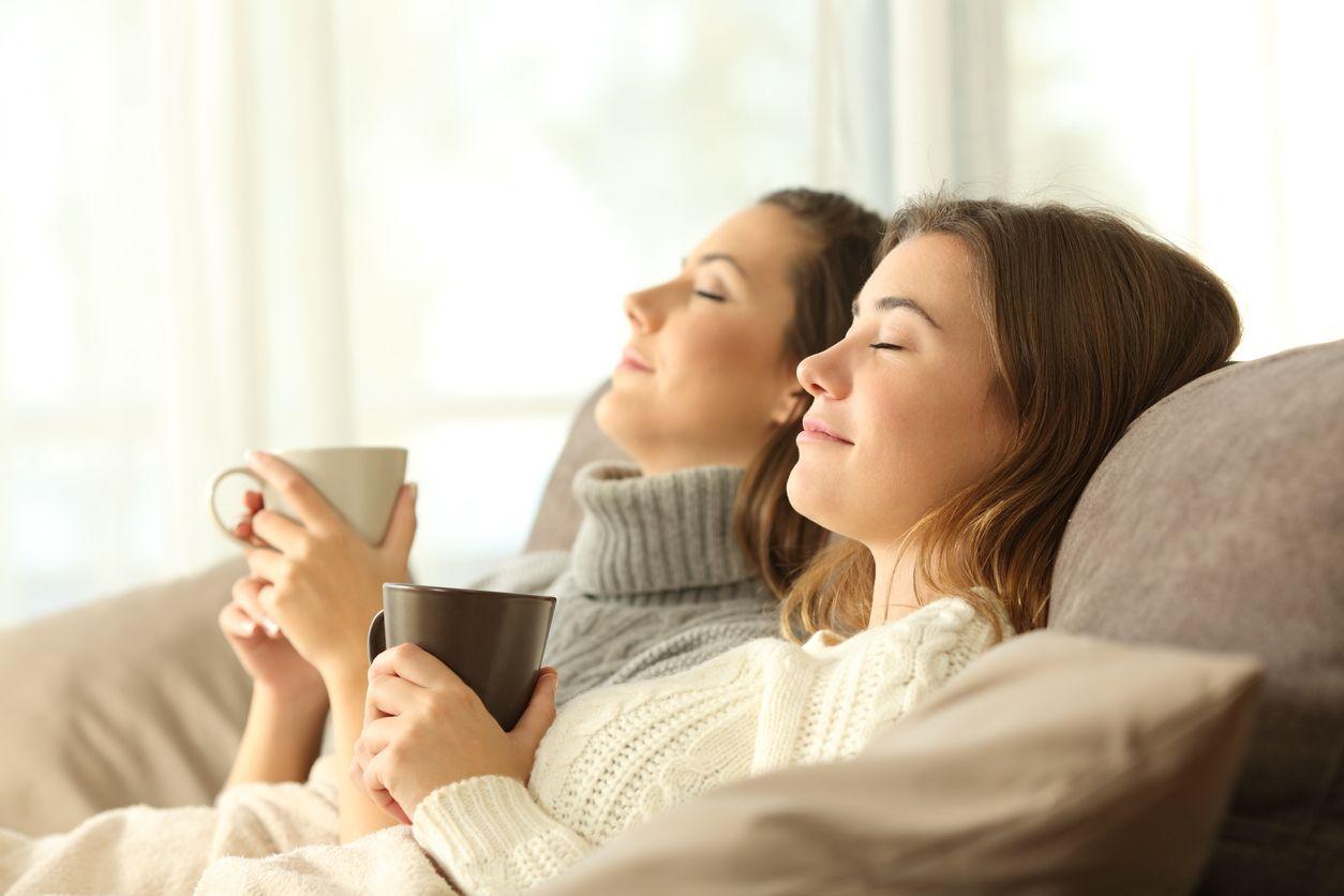 Two women relaxing on the couch with a cup of coffee.