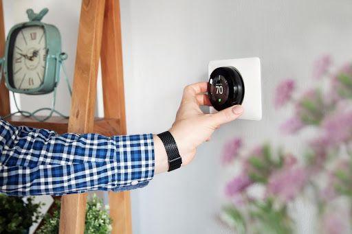 Man adjusting thermostat temperature