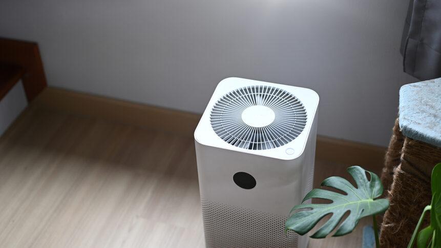 Air purifier in comfortable living room with house plant on the wooden floor.