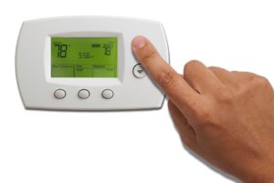 finger pushing button on hvac thermostat