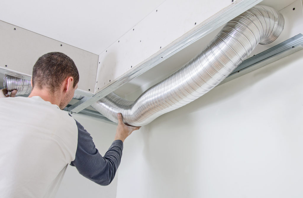 man installs ventillation system indoors