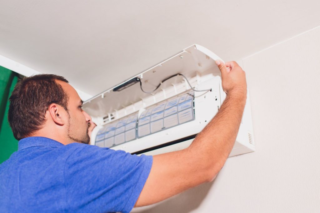 Man repairs wall air conditioner unit