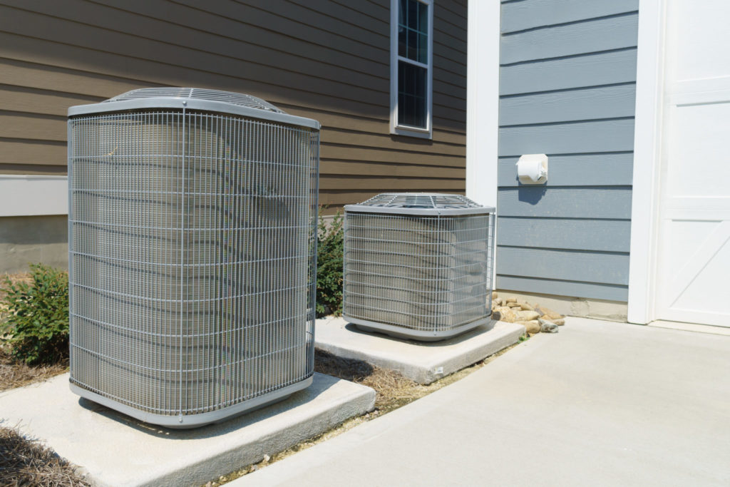 two hvac units outside home with paneled walls