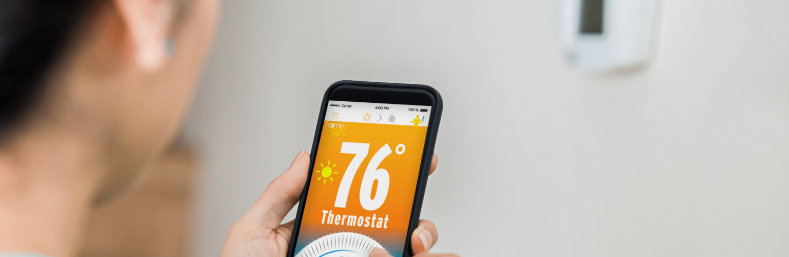 person adjusting thermostat from phone