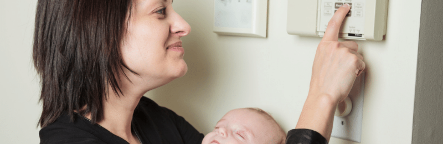 woman and baby adjusting thermostat
