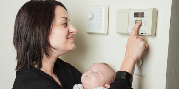 woman and baby adjusting thermostat