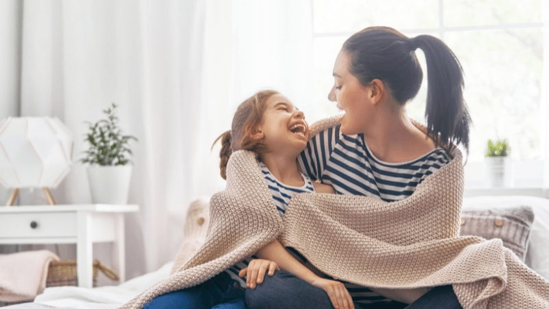 woman and daughter snuggling in blanket